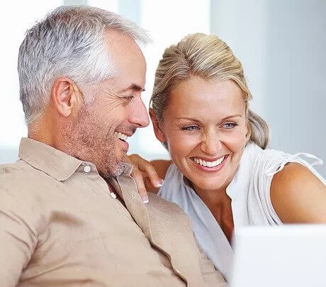 Mature couple smiling at test results on computer screen